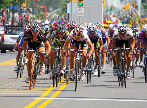 A large group of bicyclists racing down a city street.