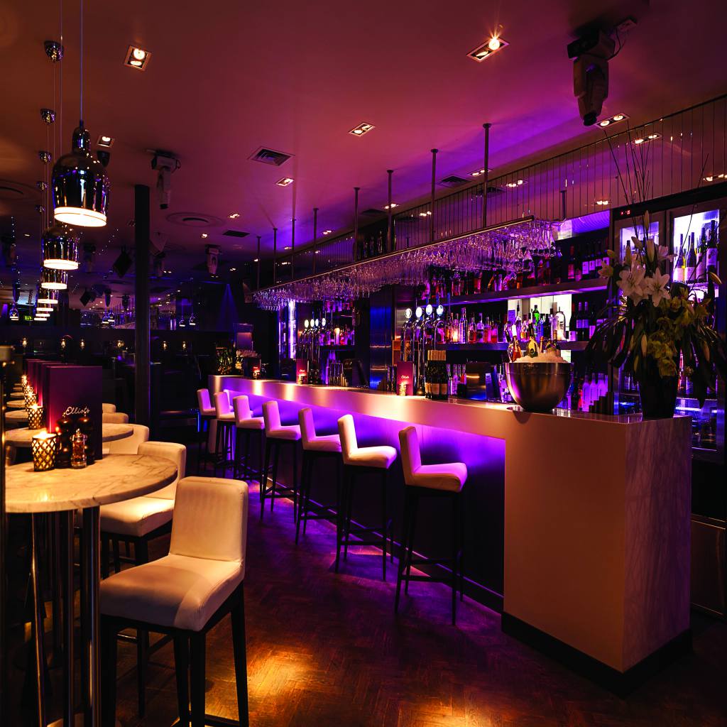 Bar Tavern Insurance – Nightclub Insurance – Bar Tavern - Nightclub - Interior photo of a bar or tavern room lit with purple and yellow lights. 